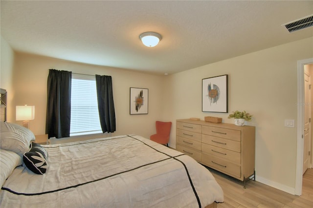 bedroom with a textured ceiling and light hardwood / wood-style flooring