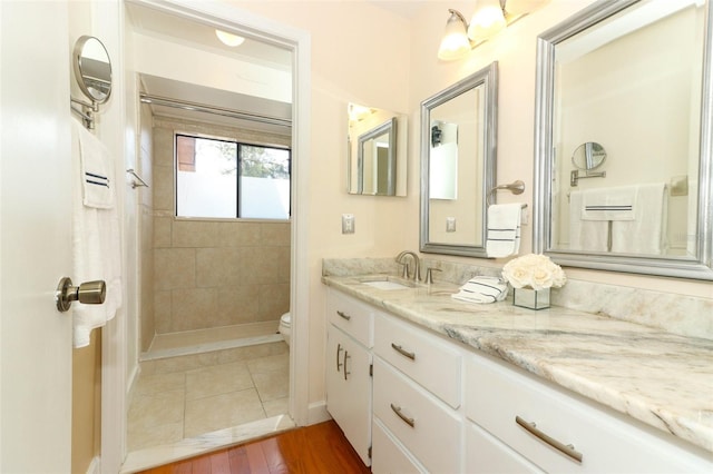 bathroom featuring tiled shower, vanity, hardwood / wood-style flooring, and toilet