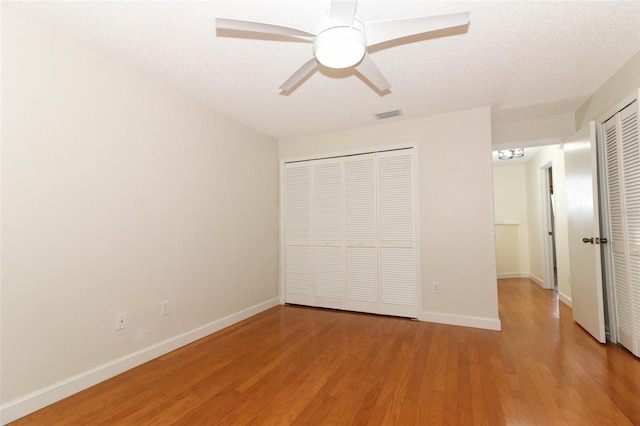 unfurnished bedroom featuring ceiling fan, light hardwood / wood-style floors, and a textured ceiling