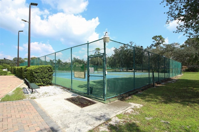 view of tennis court featuring a lawn