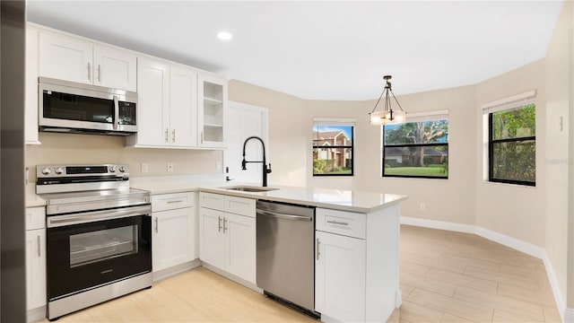 kitchen featuring white cabinets, sink, kitchen peninsula, decorative light fixtures, and stainless steel appliances