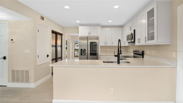 kitchen featuring sink, appliances with stainless steel finishes, kitchen peninsula, and white cabinetry