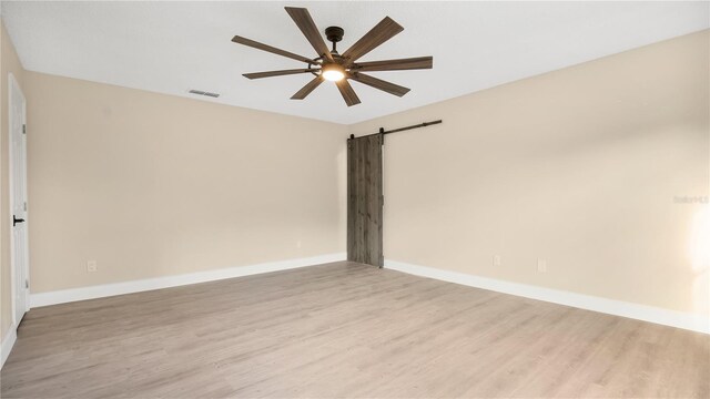 7972 Snowberry Cir, Orlando, FL 32819 - unfurnished room with a ceiling fan, visible vents, a barn door, and light wood-type flooring