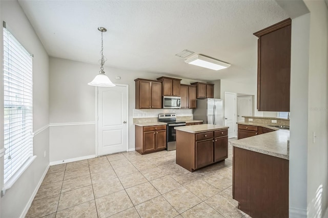 kitchen featuring a center island, tasteful backsplash, hanging light fixtures, stainless steel appliances, and light tile patterned floors