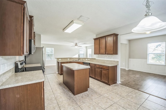 kitchen with hanging light fixtures, a healthy amount of sunlight, backsplash, and a kitchen island