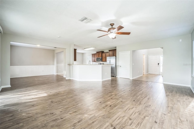 unfurnished living room featuring ceiling fan, hardwood / wood-style flooring, and sink