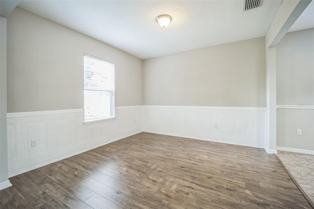 unfurnished room featuring a textured ceiling and hardwood / wood-style floors