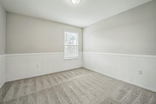 empty room with wood walls and light colored carpet