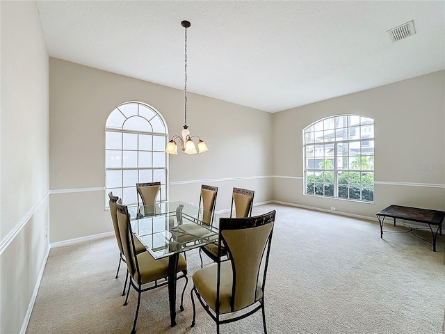 carpeted dining space featuring a textured ceiling and an inviting chandelier