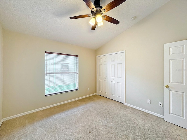 unfurnished bedroom with a closet, light colored carpet, vaulted ceiling, and ceiling fan