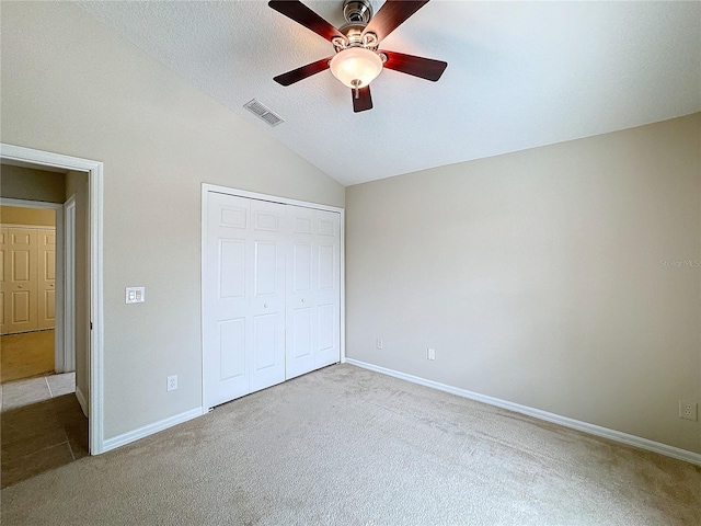 unfurnished bedroom featuring light carpet, a textured ceiling, ceiling fan, a closet, and lofted ceiling