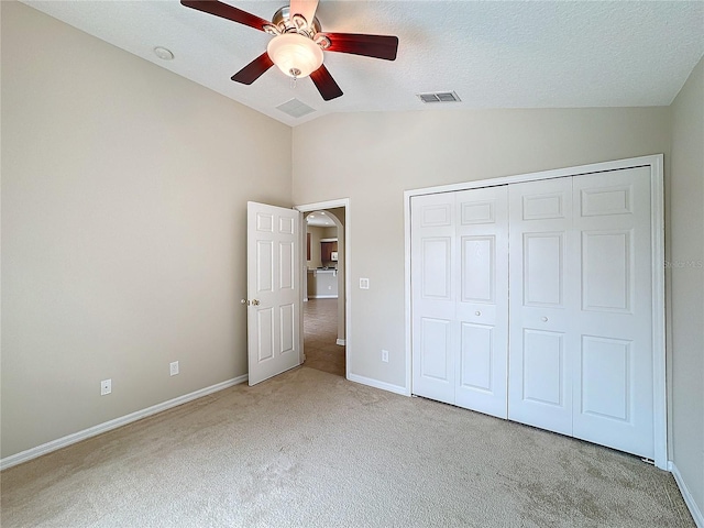 unfurnished bedroom featuring light carpet, a closet, vaulted ceiling, and ceiling fan