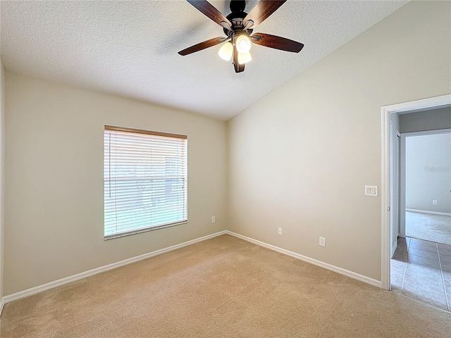 empty room featuring vaulted ceiling, ceiling fan, light colored carpet, and a textured ceiling