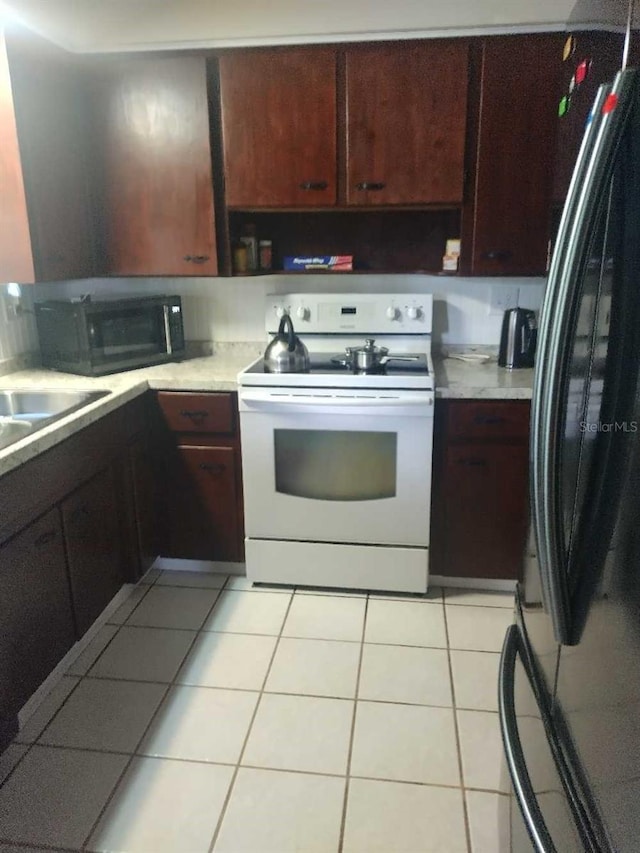 kitchen featuring sink, light tile patterned floors, and black appliances