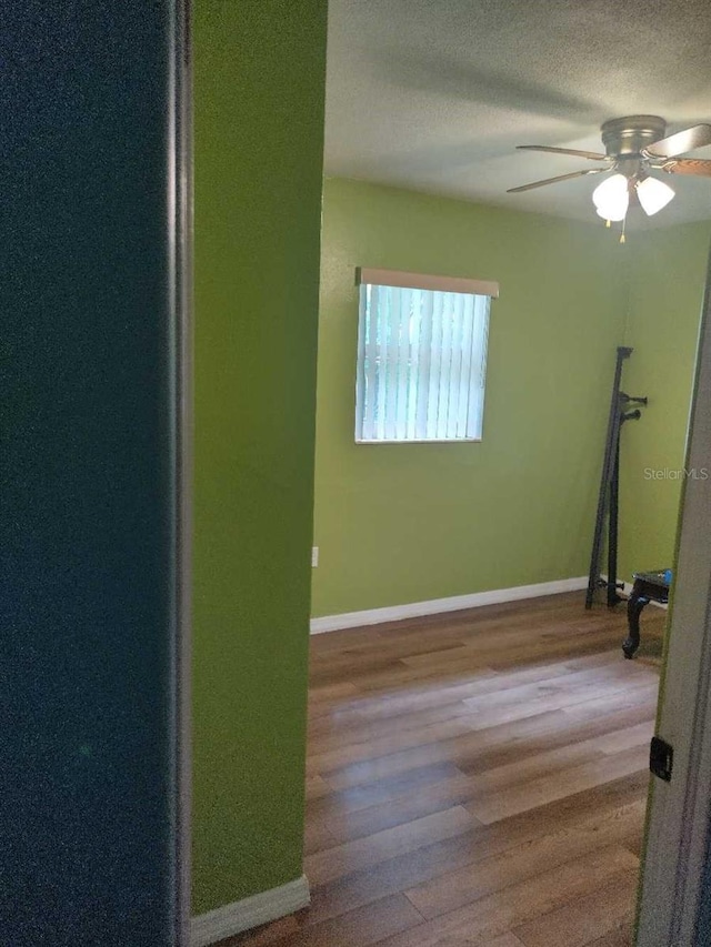 spare room featuring ceiling fan, wood-type flooring, and a textured ceiling