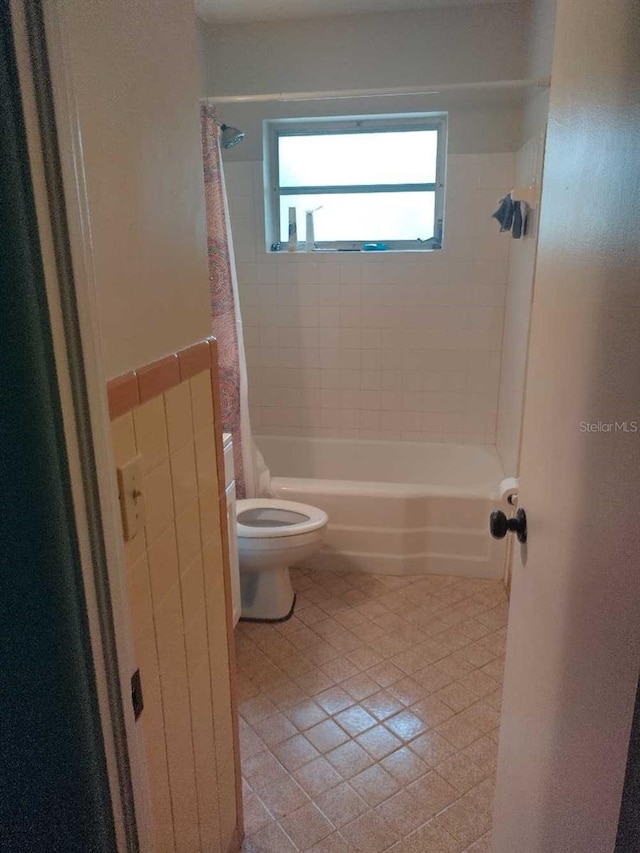 bathroom with tile patterned floors, shower / tub combo with curtain, and toilet