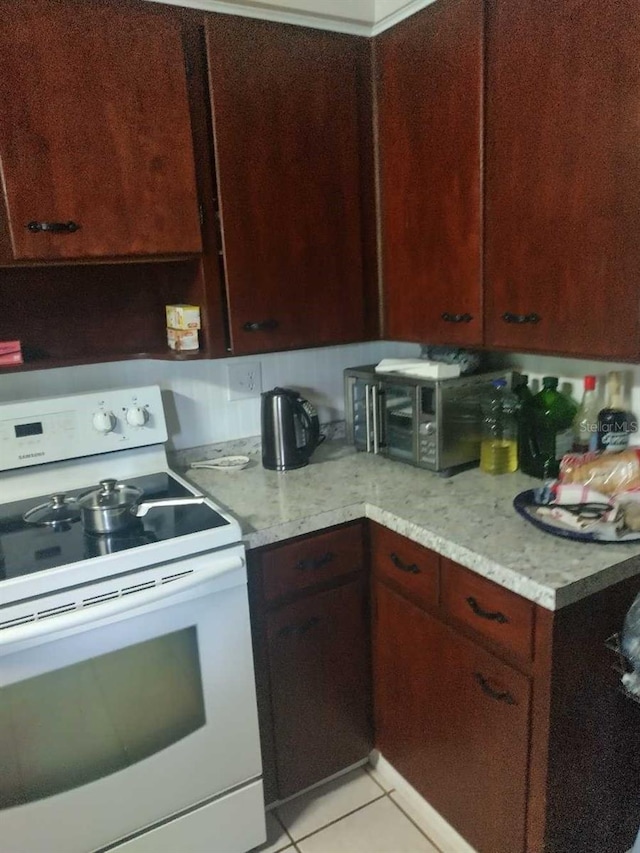 kitchen featuring white range with electric cooktop, light stone countertops, dark brown cabinetry, and light tile patterned flooring