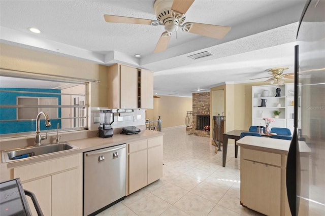 kitchen featuring light tile patterned floors, sink, stainless steel dishwasher, a textured ceiling, and a fireplace