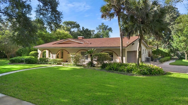 mediterranean / spanish home with cooling unit, a garage, and a front yard