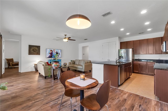 kitchen featuring light hardwood / wood-style floors, stainless steel appliances, an island with sink, and ceiling fan