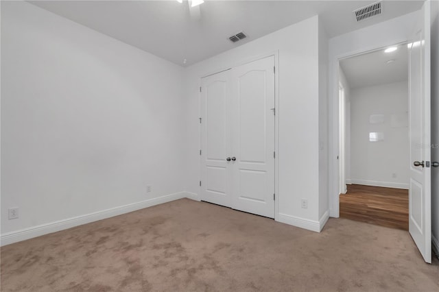 unfurnished bedroom featuring light colored carpet, a closet, and ceiling fan