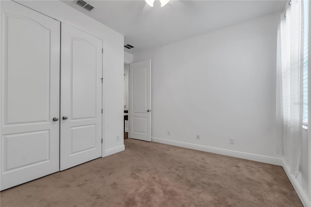 unfurnished bedroom featuring light carpet, a closet, and ceiling fan