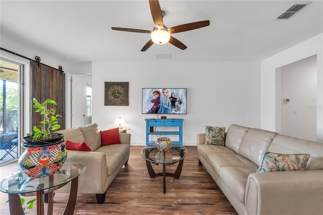 living room with dark hardwood / wood-style floors, a barn door, and ceiling fan