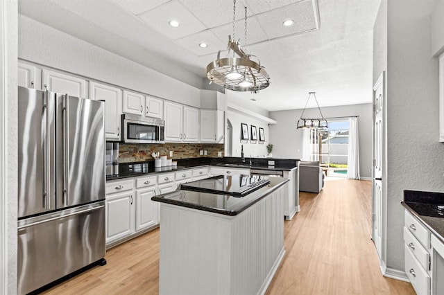 kitchen with light hardwood / wood-style floors, a center island, white cabinets, stainless steel appliances, and backsplash