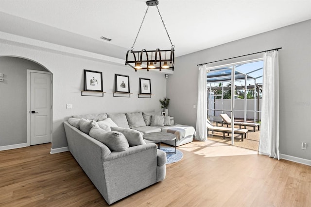 living room featuring wood-type flooring and an inviting chandelier