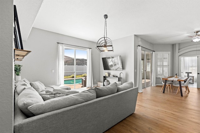 living room featuring a textured ceiling, ceiling fan with notable chandelier, and hardwood / wood-style floors