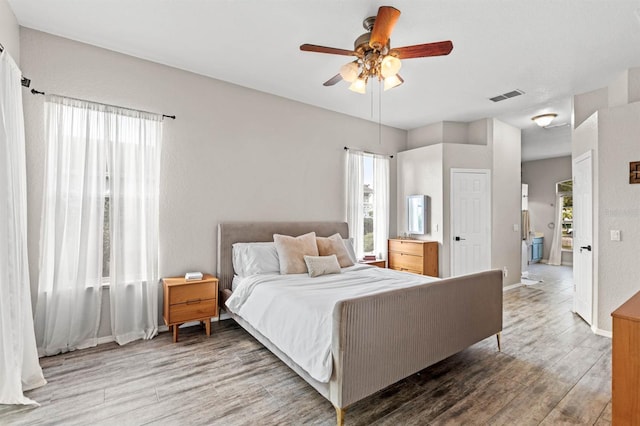 bedroom featuring hardwood / wood-style floors, ceiling fan, and ensuite bath