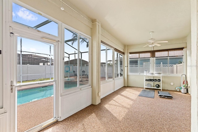 unfurnished sunroom featuring ceiling fan and a pool