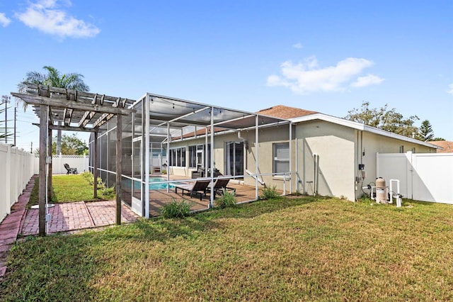 back of property featuring a lawn, a fenced in pool, a patio area, and glass enclosure