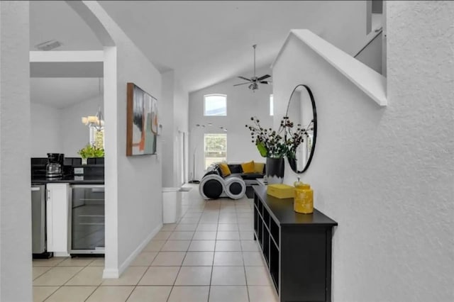 tiled foyer entrance featuring high vaulted ceiling, wine cooler, and ceiling fan with notable chandelier