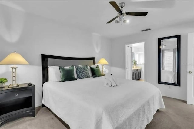 bedroom with ceiling fan, ensuite bath, and light carpet