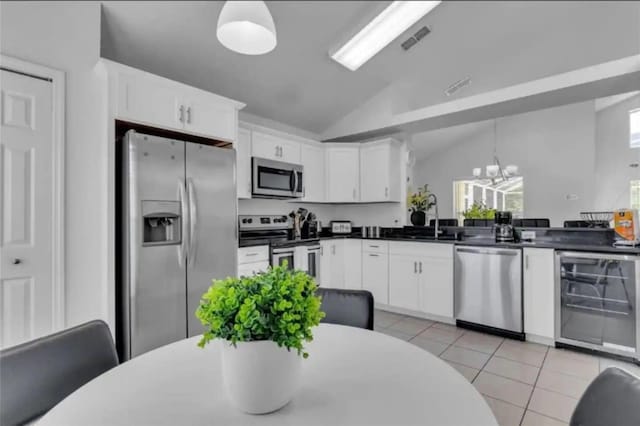 kitchen with appliances with stainless steel finishes, decorative light fixtures, light tile patterned floors, and white cabinets