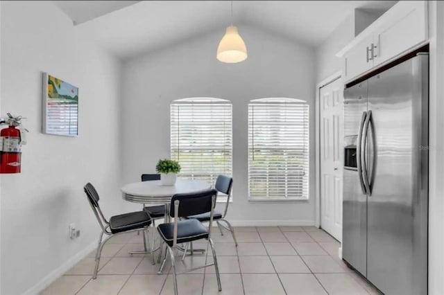 dining space featuring light tile patterned floors and vaulted ceiling