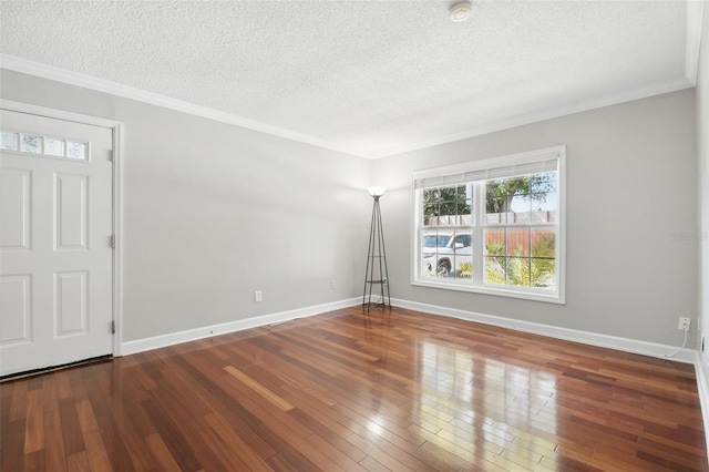 empty room with crown molding, a textured ceiling, baseboards, and hardwood / wood-style flooring