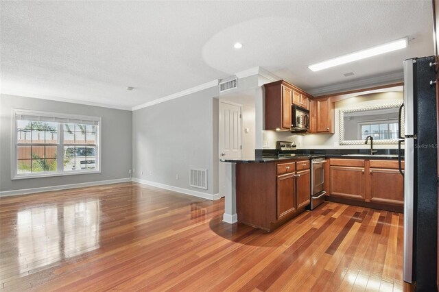 kitchen with stainless steel appliances, a sink, wood finished floors, visible vents, and dark countertops