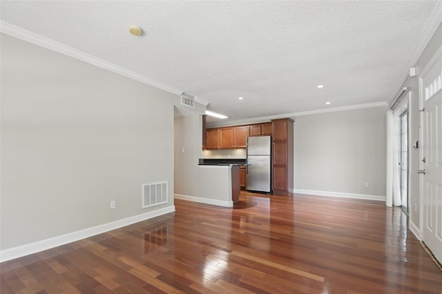 unfurnished living room with baseboards, visible vents, dark wood-type flooring, a textured ceiling, and crown molding