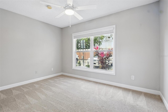 carpeted spare room with ceiling fan and baseboards