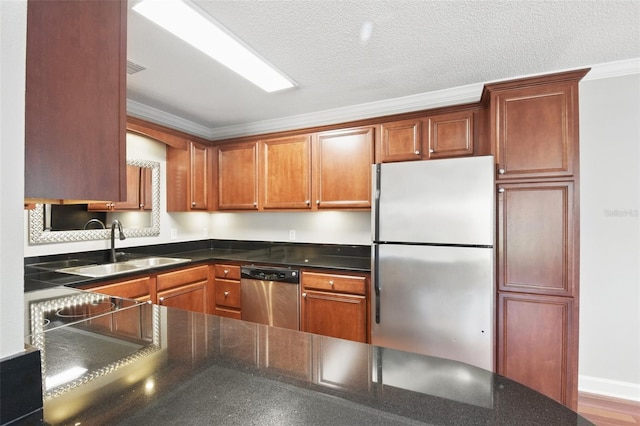 kitchen featuring appliances with stainless steel finishes, a sink, a textured ceiling, and ornamental molding