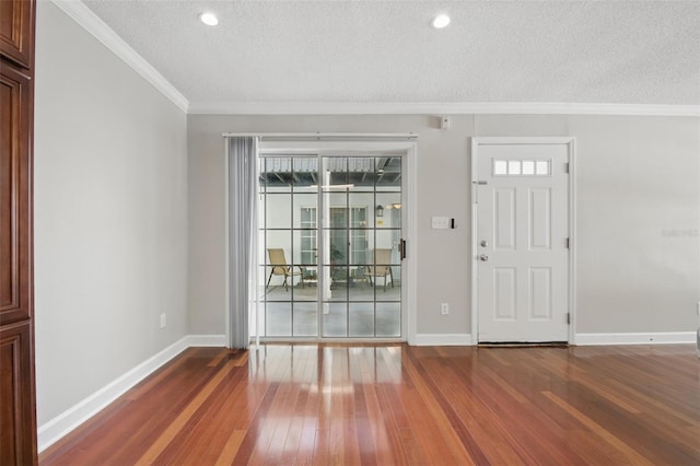 foyer with crown molding, a textured ceiling, baseboards, and wood finished floors