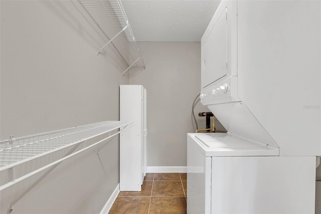 laundry room with laundry area, baseboards, stacked washer / dryer, tile patterned flooring, and a textured ceiling