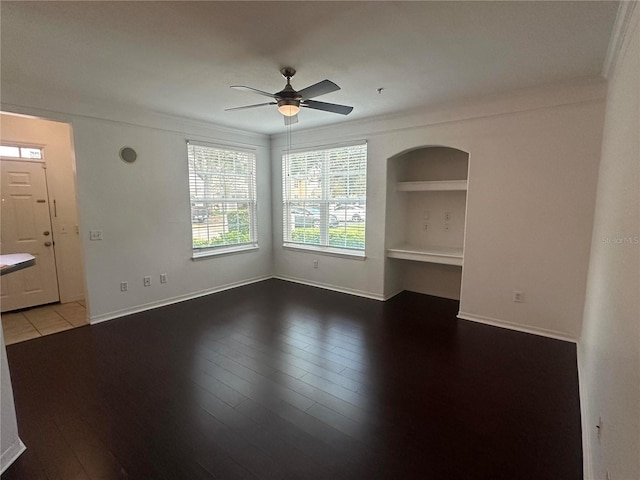 unfurnished room featuring crown molding, ceiling fan, built in shelves, and hardwood / wood-style floors