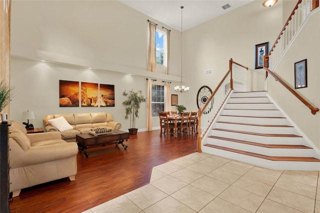 living room with an inviting chandelier, a towering ceiling, and light hardwood / wood-style floors