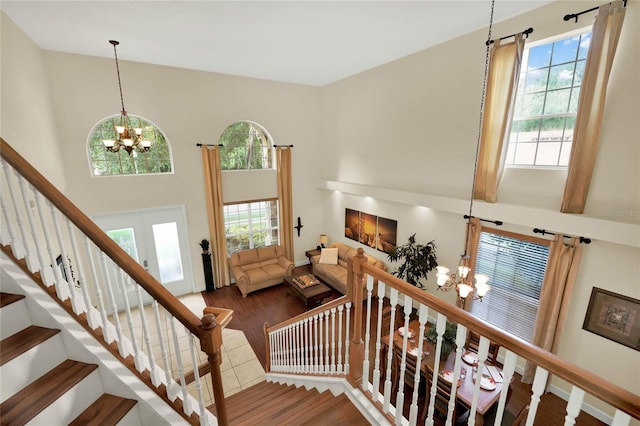 stairway featuring an inviting chandelier, a healthy amount of sunlight, and hardwood / wood-style floors