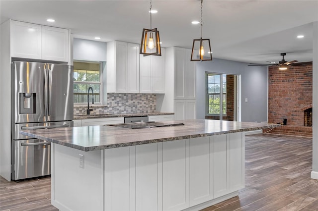 kitchen with white cabinetry, sink, a center island, stainless steel fridge with ice dispenser, and light hardwood / wood-style flooring