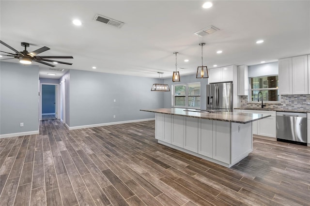 kitchen with white cabinets, a kitchen island, stainless steel appliances, and pendant lighting