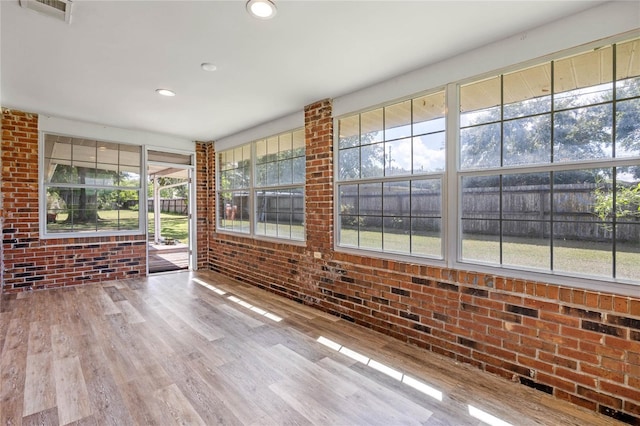 interior space featuring hardwood / wood-style flooring and brick wall